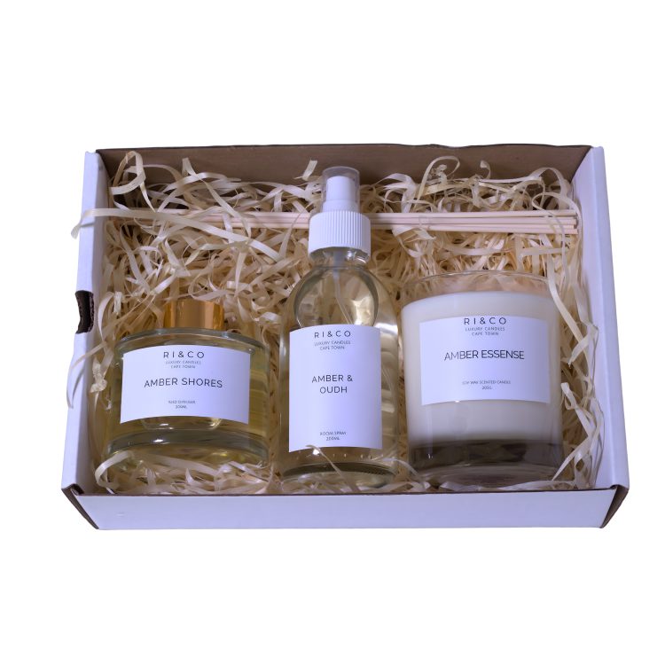 amber luxe gift set with amber shores diffuser, amber and oudh room spray, and amber essence candle arranged in luxury packaging
