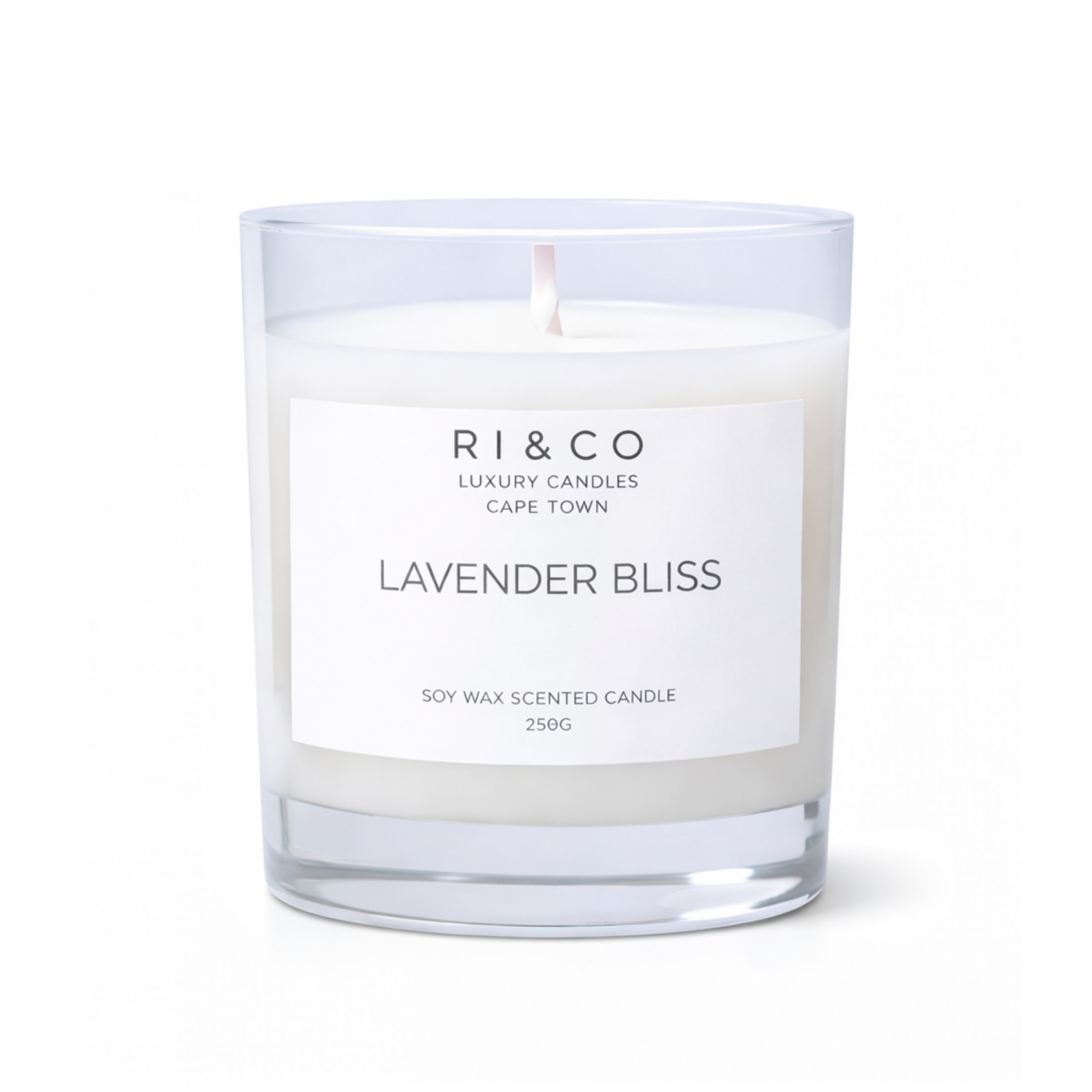 RI & CO Lavender Bliss luxury soy candle on bedside table with fresh lavender stems in a peaceful bedroom setting