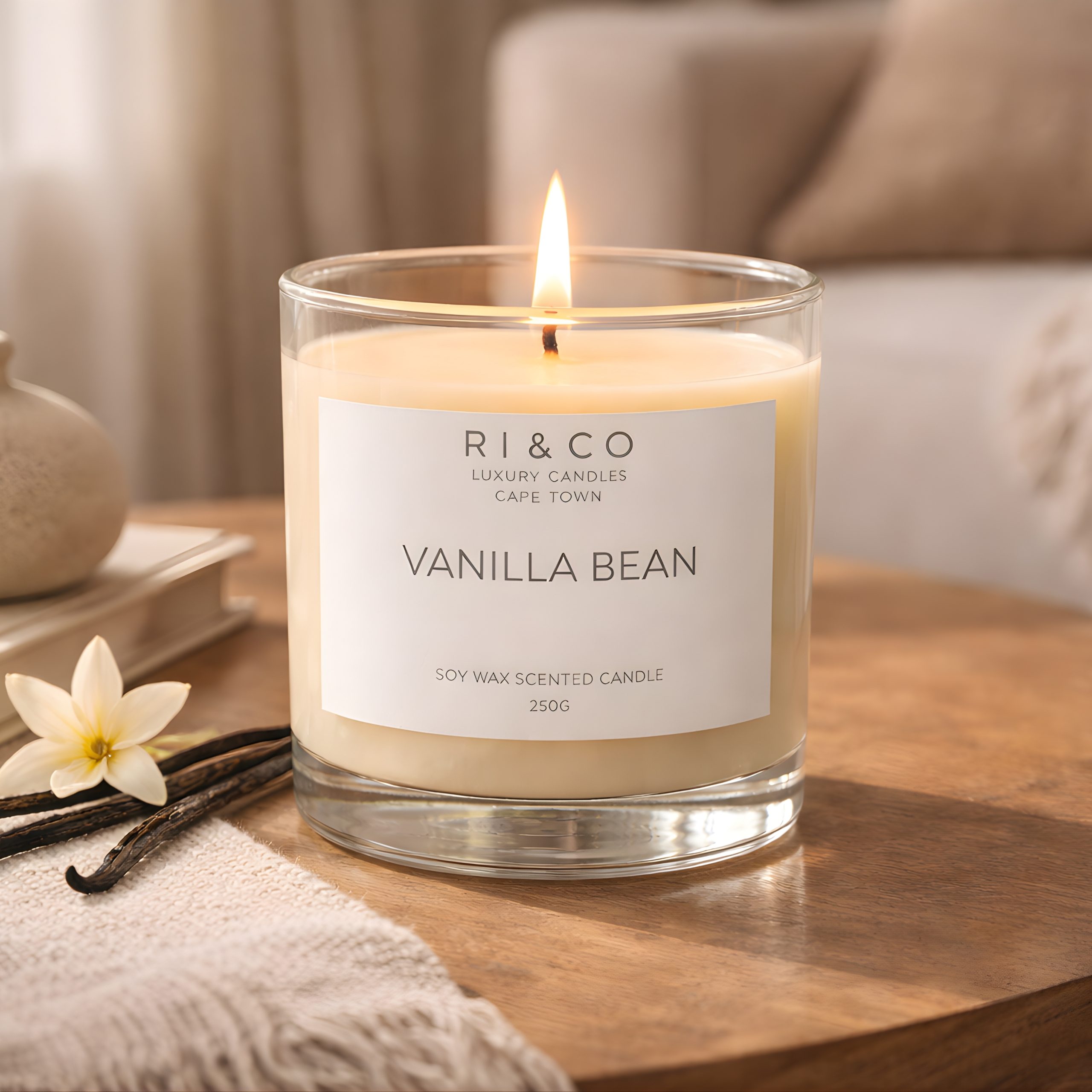 RI & CO Vanilla Bean luxury soy candle styled on wooden coffee table with vanilla pods in a cozy living room setting