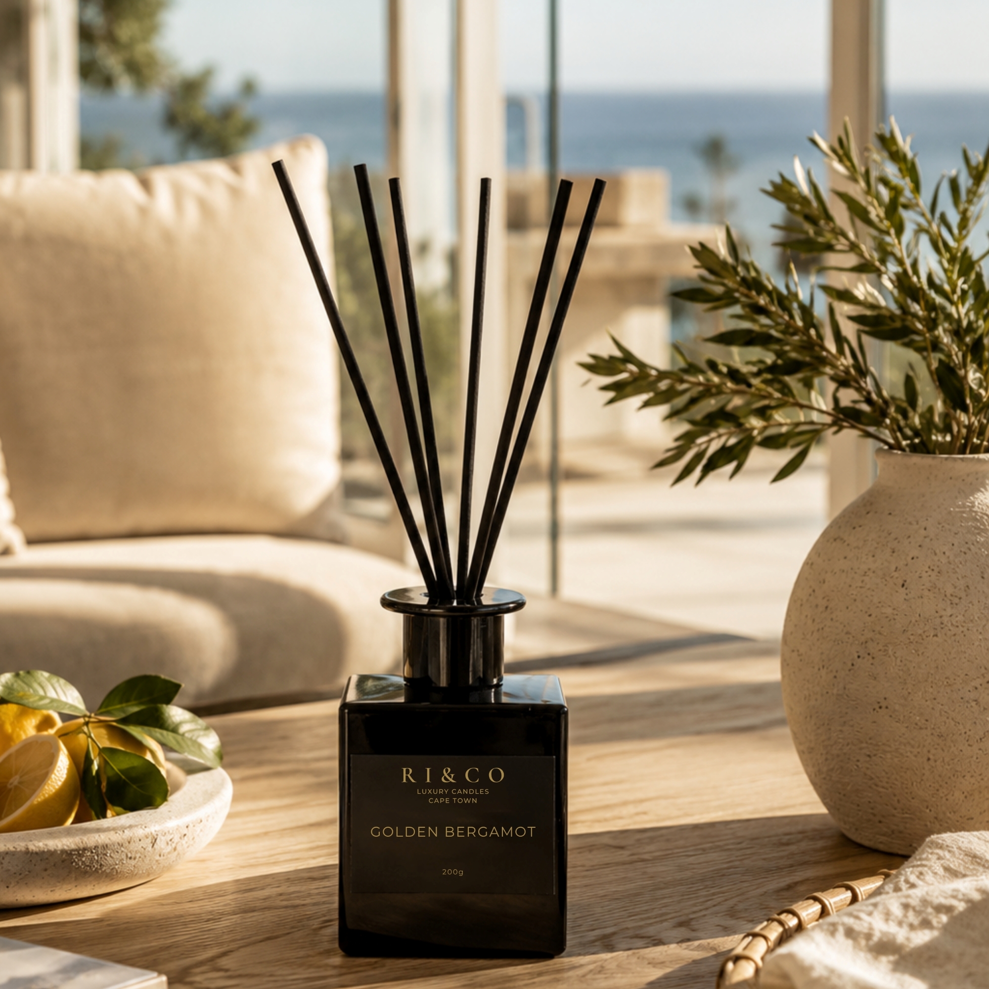 RI&CO Golden Bergamot reed diffuser styled in a bright coastal-inspired luxury living space