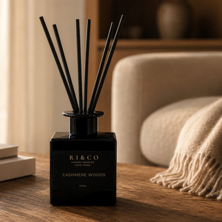 RI&CO Cashmere Woods reed diffuser on a wooden coffee table with a cashmere throw in a luxury lounge interior