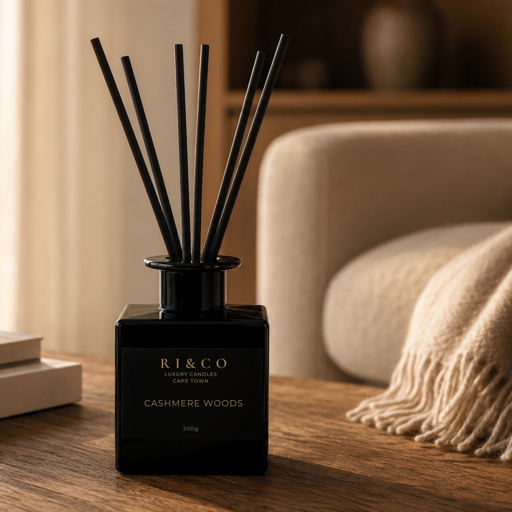 RI&CO Cashmere Woods reed diffuser on a wooden coffee table with a cashmere throw in a luxury lounge interior