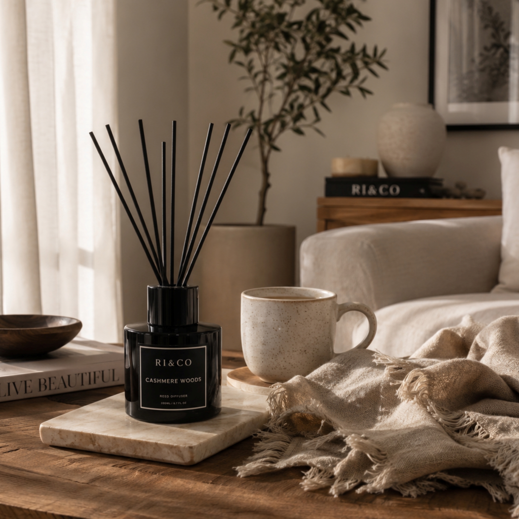 How to Create a Calming Home Environment Through Fragrance | RI&CO Luxury living room featuring a RI&CO Cashmere Woods reed diffuser creating a calm and relaxing home environment.